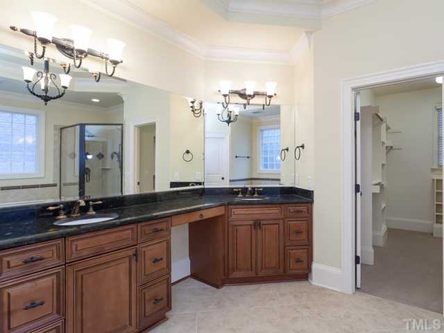 12816 River Dance Drive Raleigh, NC 27613 - Photo 16 of 25 Highlights of the freshly-painted master bath include custom cabinets with ample storage, granite counter tops, two separate sinks, a vanity area, heavy crown molding, and ceramic tile flooring.