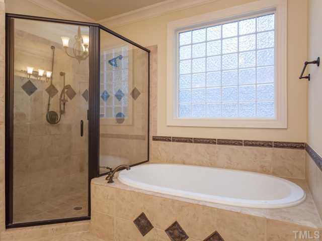 12816 River Dance Drive Raleigh, NC 27613 - Photo 17 of 25 For your bath needs, the master bath offers a large walk -in shower with dual shower heads, a jetted tub with tile surround, and a glass-block window that provides both privacy and natural light.