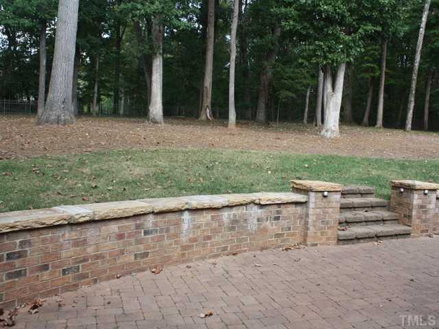 12816 River Dance Drive Raleigh, NC 27613 - Photo 25 of 25 This is the backyard that you have been dreaming of! It is has a fenced yard with majestic hardwood trees and a large paver-stone patio with a brick and stone wall. The yard goes beyond the fence in the back right portion of the property.
