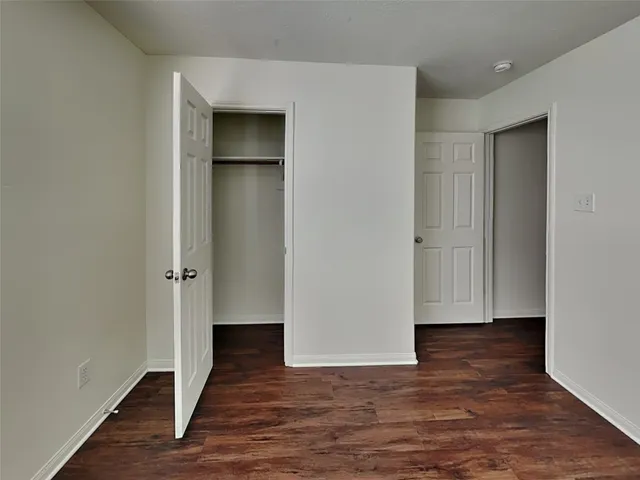 a view of an empty room with wooden floor and closet