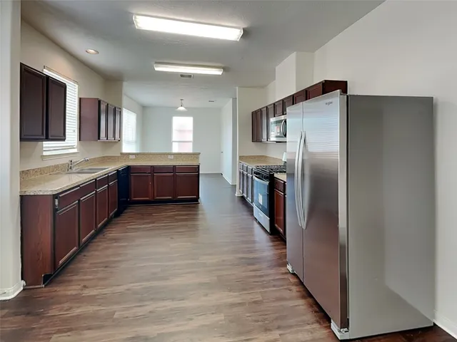 a large kitchen with stainless steel appliances granite countertop a large counter top and wooden floors