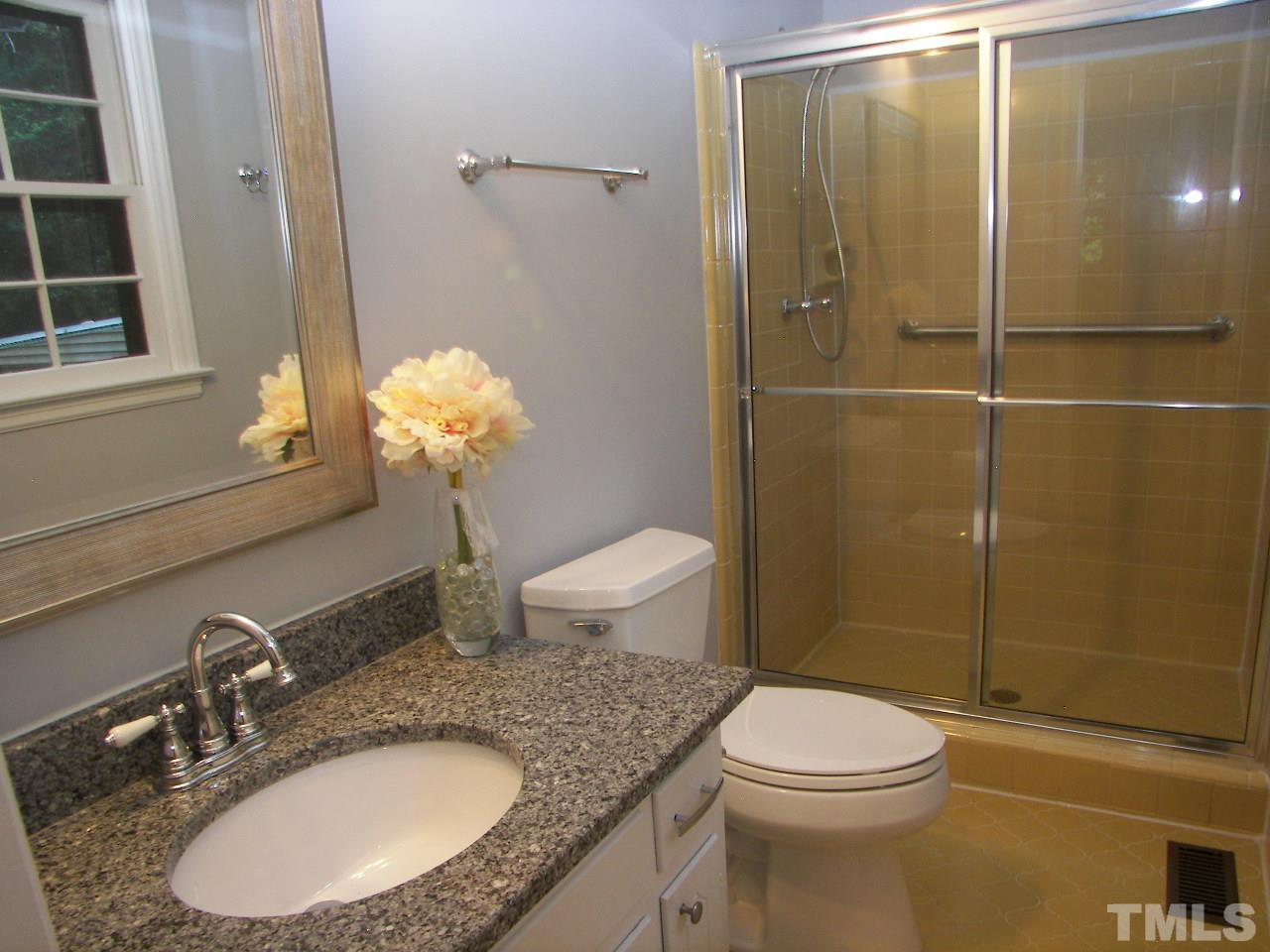 6729 Johnsdale Road Raleigh, NC 27615 - Photo 14 of 25 a bathroom with a granite countertop toilet a sink and shower