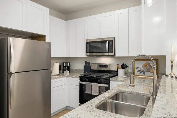 a kitchen with a refrigerator a microwave a sink and cabinets