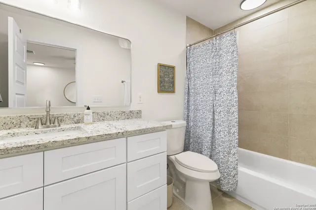 a bathroom with a granite countertop toilet sink and a mirror