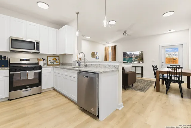 a kitchen with a stove a sink a microwave a dining table and chairs