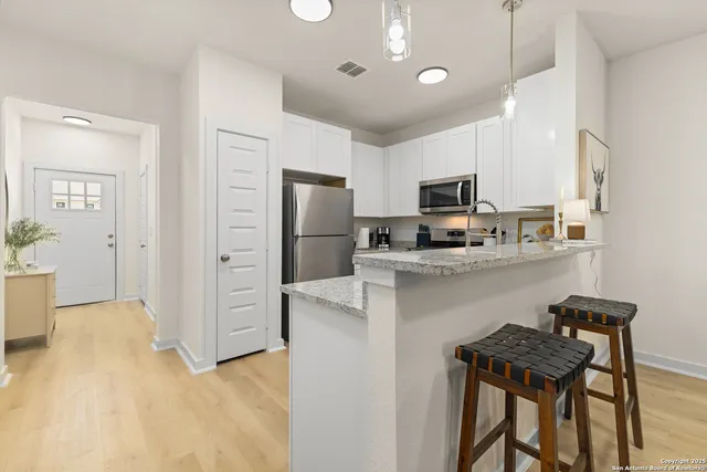 a kitchen with stainless steel appliances granite countertop a refrigerator a sink dishwasher a stove and a refrigerator with wooden floor