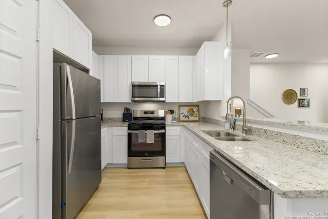 a kitchen with kitchen island granite countertop a sink stainless steel appliances and cabinets