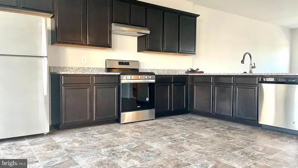 a kitchen with kitchen island granite countertop a refrigerator stove and sink