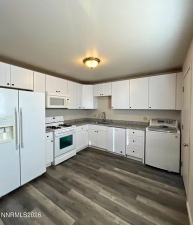 a kitchen with granite countertop white cabinets and white appliances