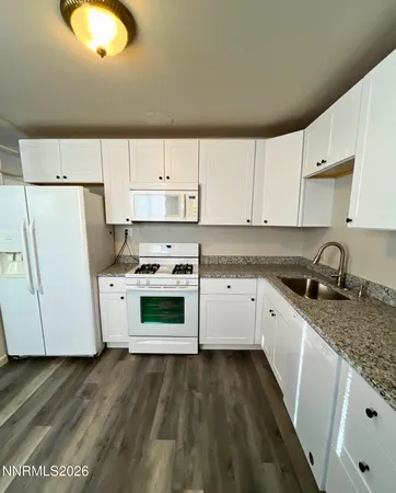 a kitchen with granite countertop white cabinets and white appliances