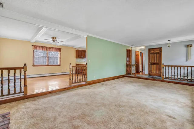a living room with stainless steel appliances kitchen island granite countertop a stove a sink a refrigerator white cabinets and wooden floor