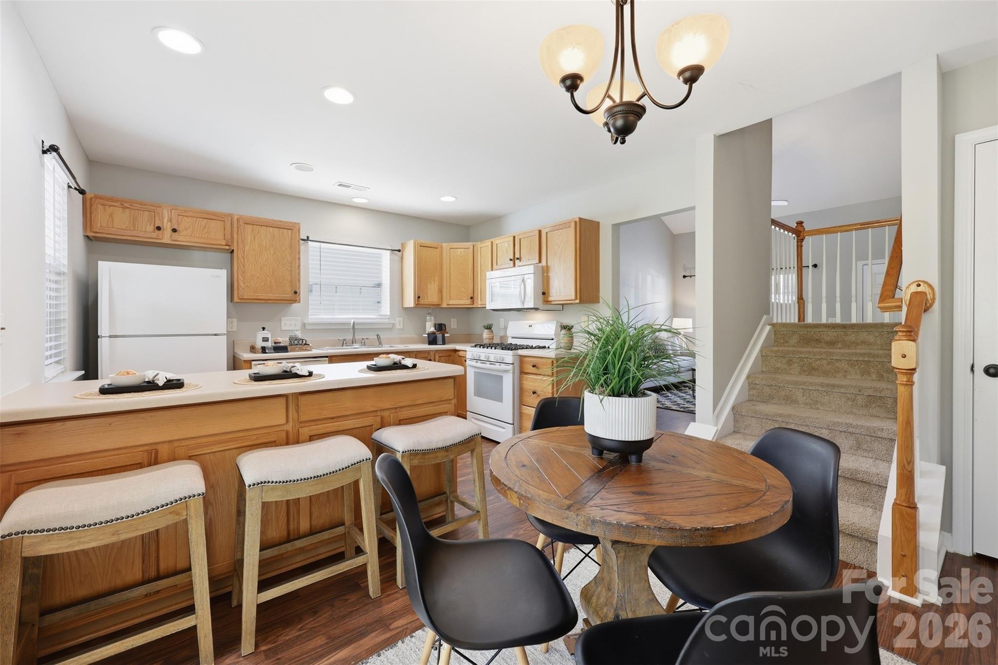 212 Primrose Walk Fort Mill, SC 29715 - Photo 9 of 37 a kitchen with stainless steel appliances granite countertop a sink a stove a dining table and chairs with wooden floor