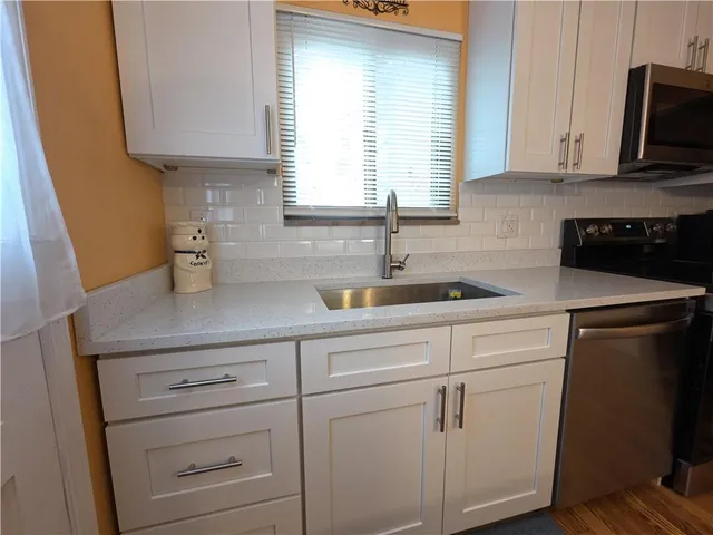 a kitchen with cabinets appliances a sink and a window