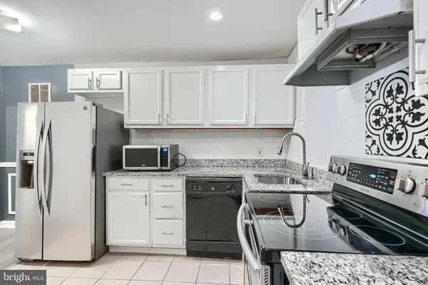a kitchen with stainless steel appliances granite countertop a stove a refrigerator and a sink