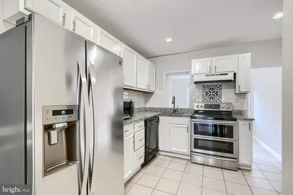 a kitchen with stainless steel appliances granite countertop a refrigerator and a stove top oven