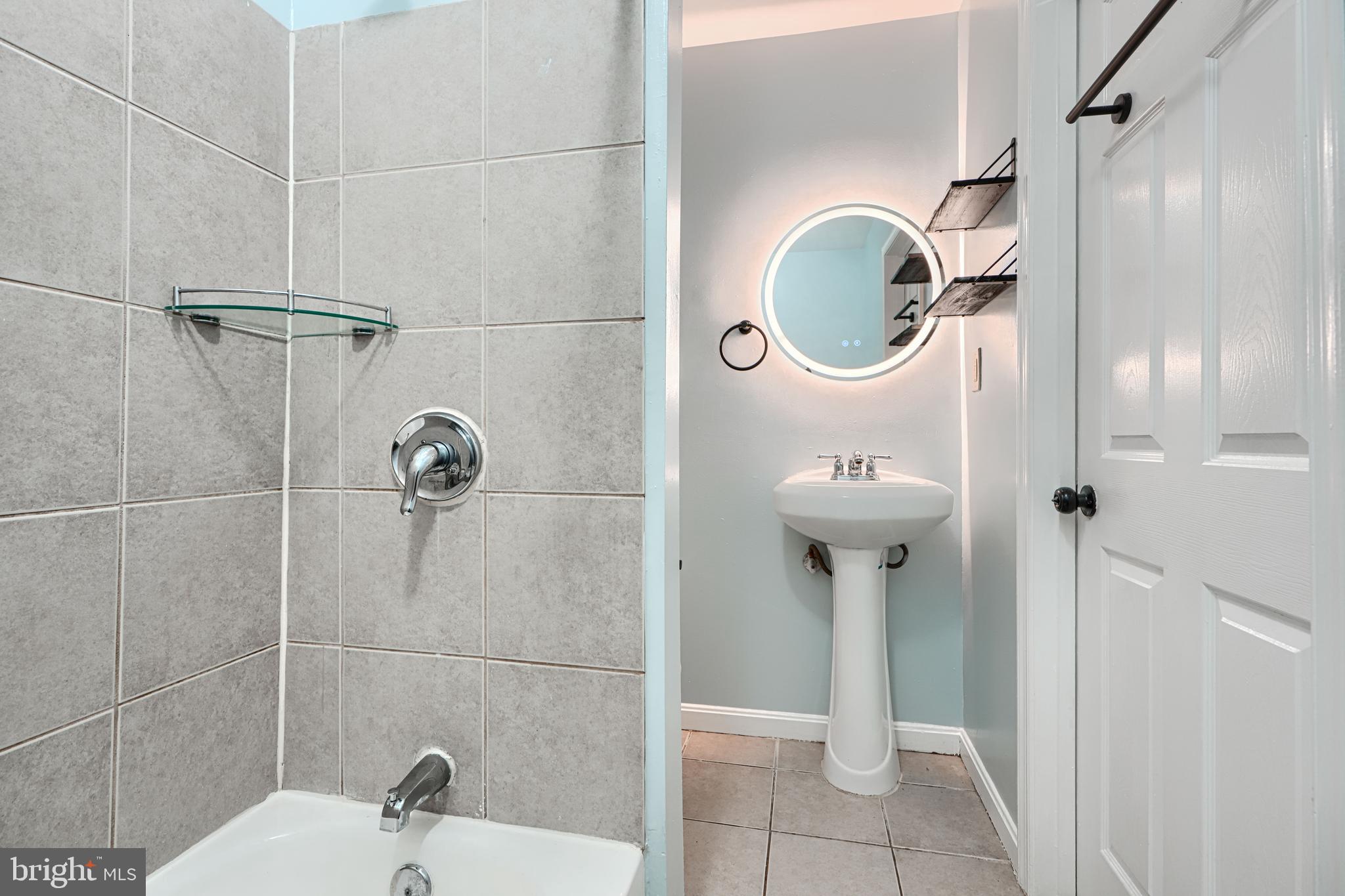 1127 Sargeant Street Baltimore, MD 21223 - Photo 22 of 30 a bathroom with a sink a mirror and glass door
