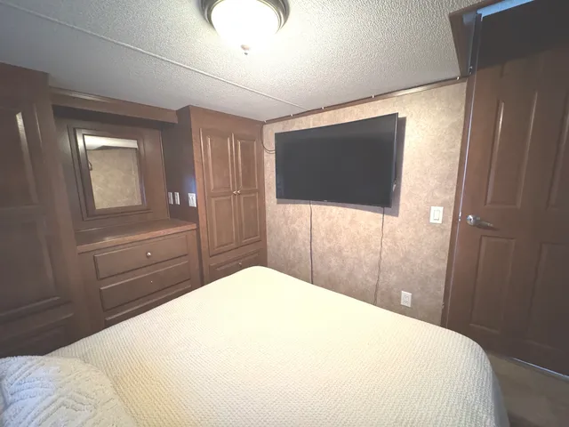 a bedroom with a bed and a flat tv screen on dresser