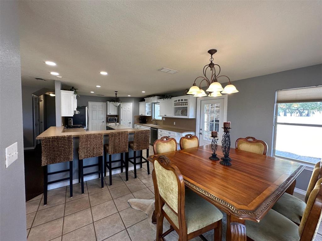 2901 Wind Mill Court Tolar, TX 76476 - Photo 6 of 38 a dining room with wooden floor a chandelier a wooden table and chairs
