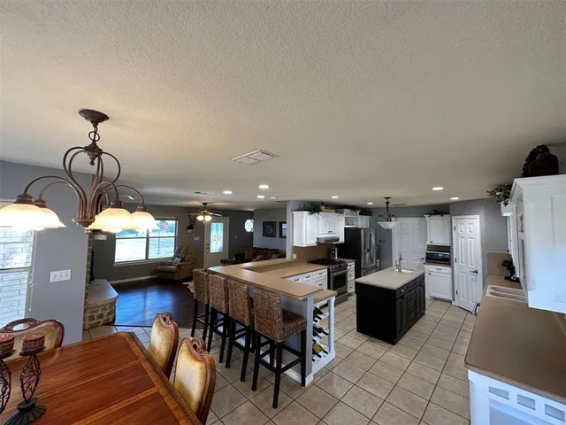 a open kitchen with stainless steel appliances kitchen island granite countertop a refrigerator a stove a oven a sink with island and chairs