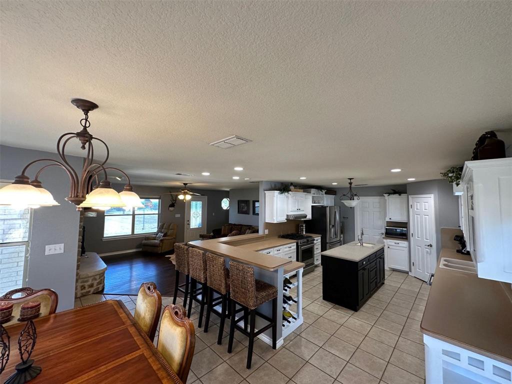 2901 Wind Mill Court Tolar, TX 76476 - Photo 9 of 38 a open kitchen with stainless steel appliances kitchen island granite countertop a refrigerator a stove a oven a sink with island and chairs