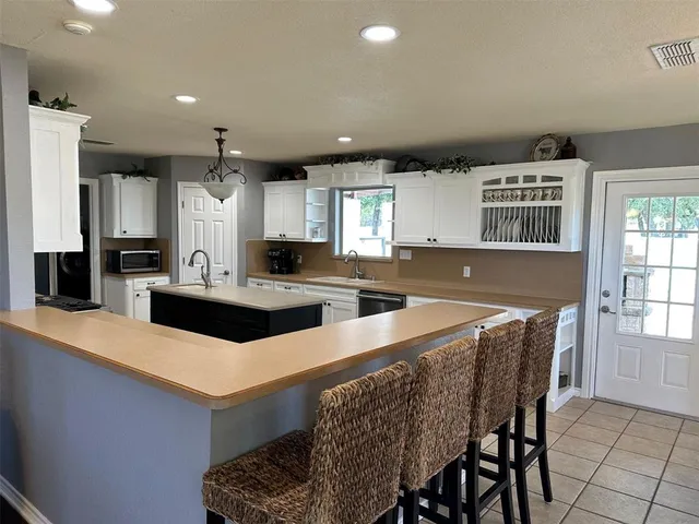 a kitchen with stainless steel appliances granite countertop a sink a stove a refrigerator a microwave oven with white cabinets and wooden floor