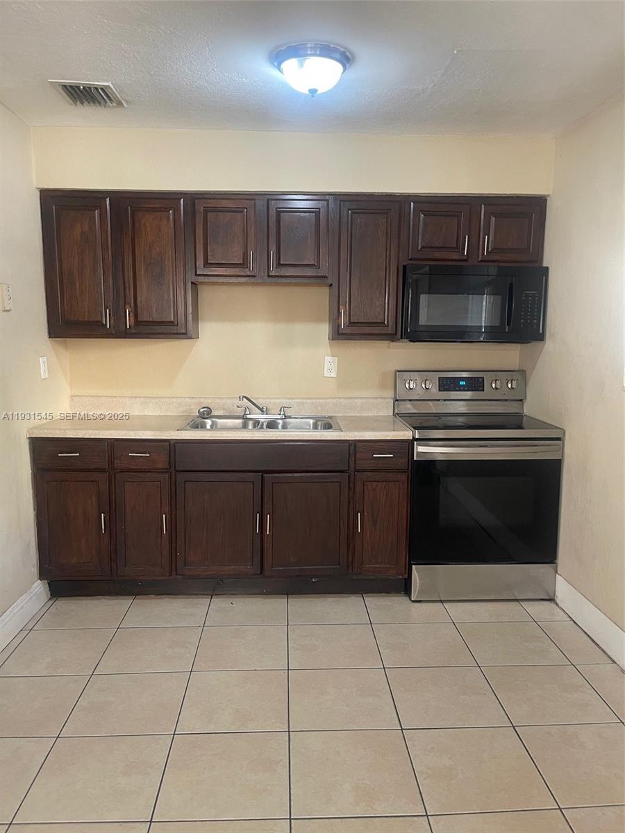 3031 Northwest 134th Street, Unit 1 Opa-Locka, FL 33054 - Photo 2 of 8 a kitchen with a sink and a stove top oven