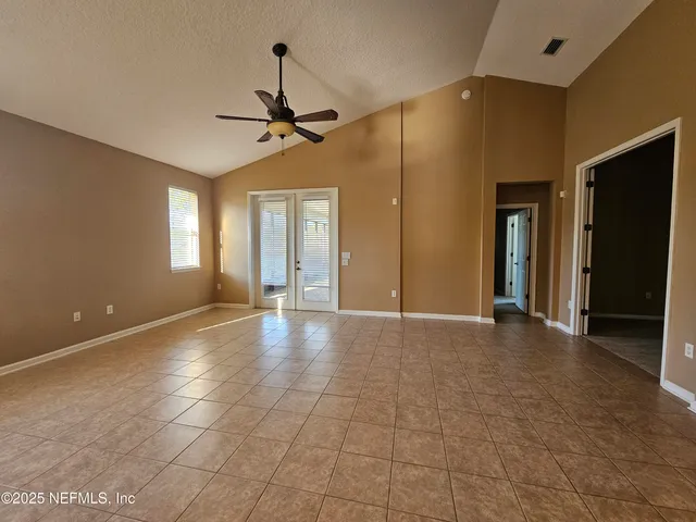 a view of a livingroom with a chandelier fan and windows