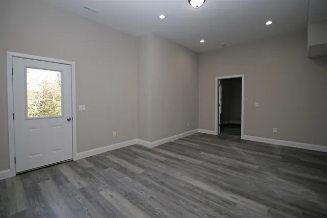 a view of an empty room with wooden floor and closet