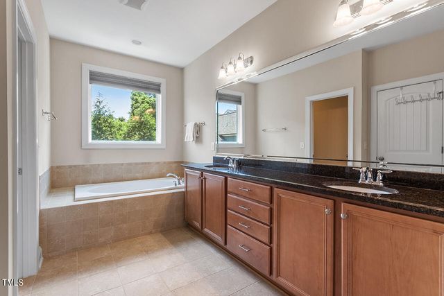 a bathroom with a bathtub double vanity sink and a large mirror