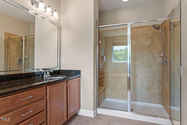 a bathroom with a granite countertop sink a mirror and shower