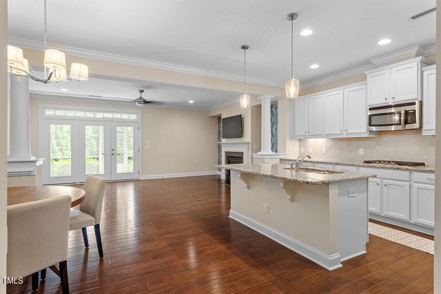 a large kitchen with cabinets chairs and wooden floor