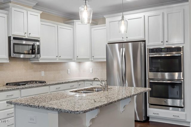a kitchen with granite countertop a sink stove and refrigerator