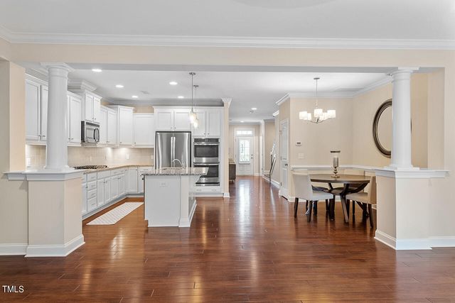 a kitchen with a dining table chairs and wooden floor
