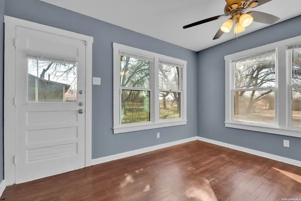 an empty room with windows and a chandelier fan
