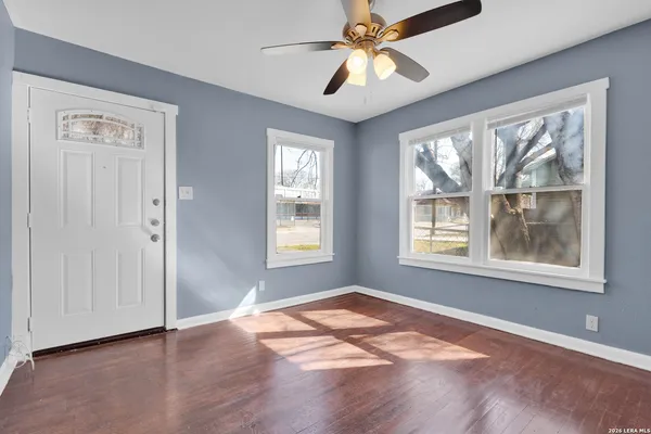 a view of an empty room with wooden floor and a window