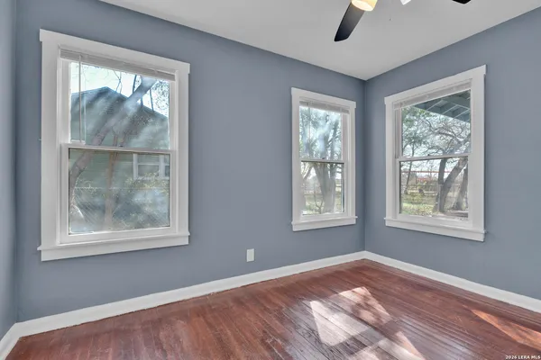 a view of an empty room with wooden floor and a window