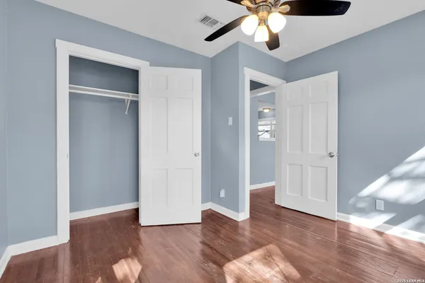 a view of an empty room with wooden floor and cabinet