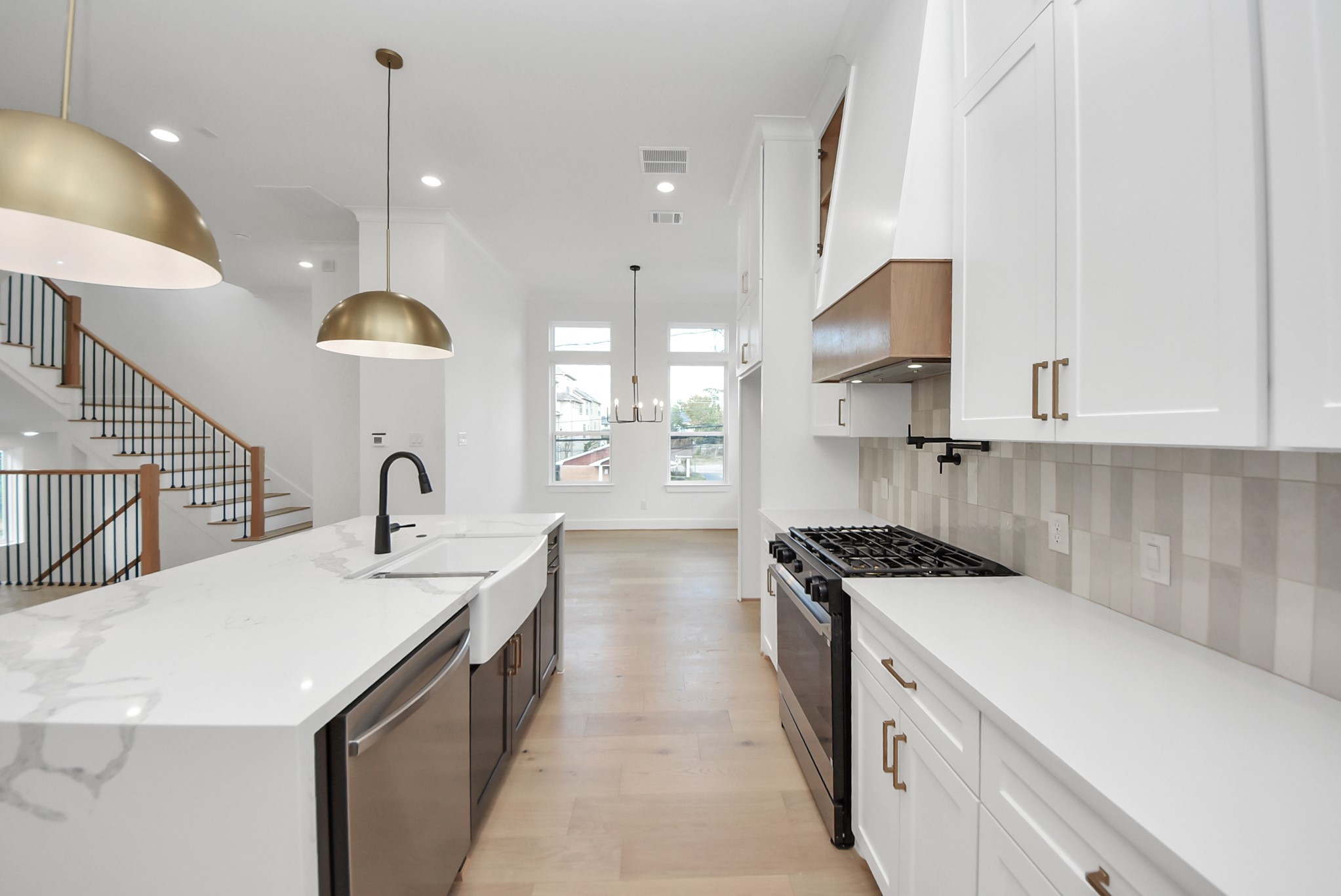 923 Fisher Street, Unit A Houston, TX 77018 - Photo 14 of 47 A sleek, entertainer-friendly kitchen with white cabinetry, a spacious marble island, and elegant brass pendant lighting. The built-in gas cooktop, open layout, and natural light make this space ideal for both daily living and hosting.
