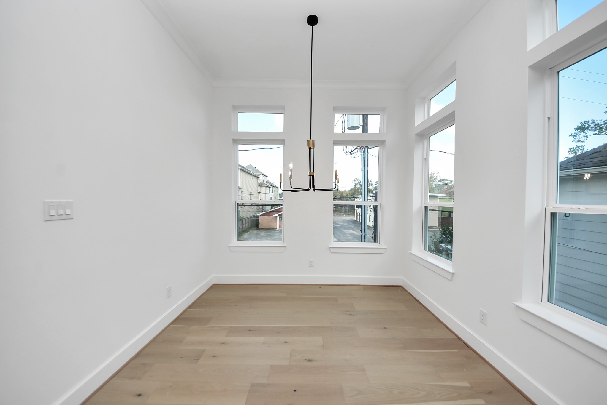 923 Fisher Street, Unit A Houston, TX 77018 - Photo 15 of 47 A bright dining area filled with natural light from large windows, complemented by hardwood floors and a modern chandelier—an inviting space for everyday meals and casual entertaining.