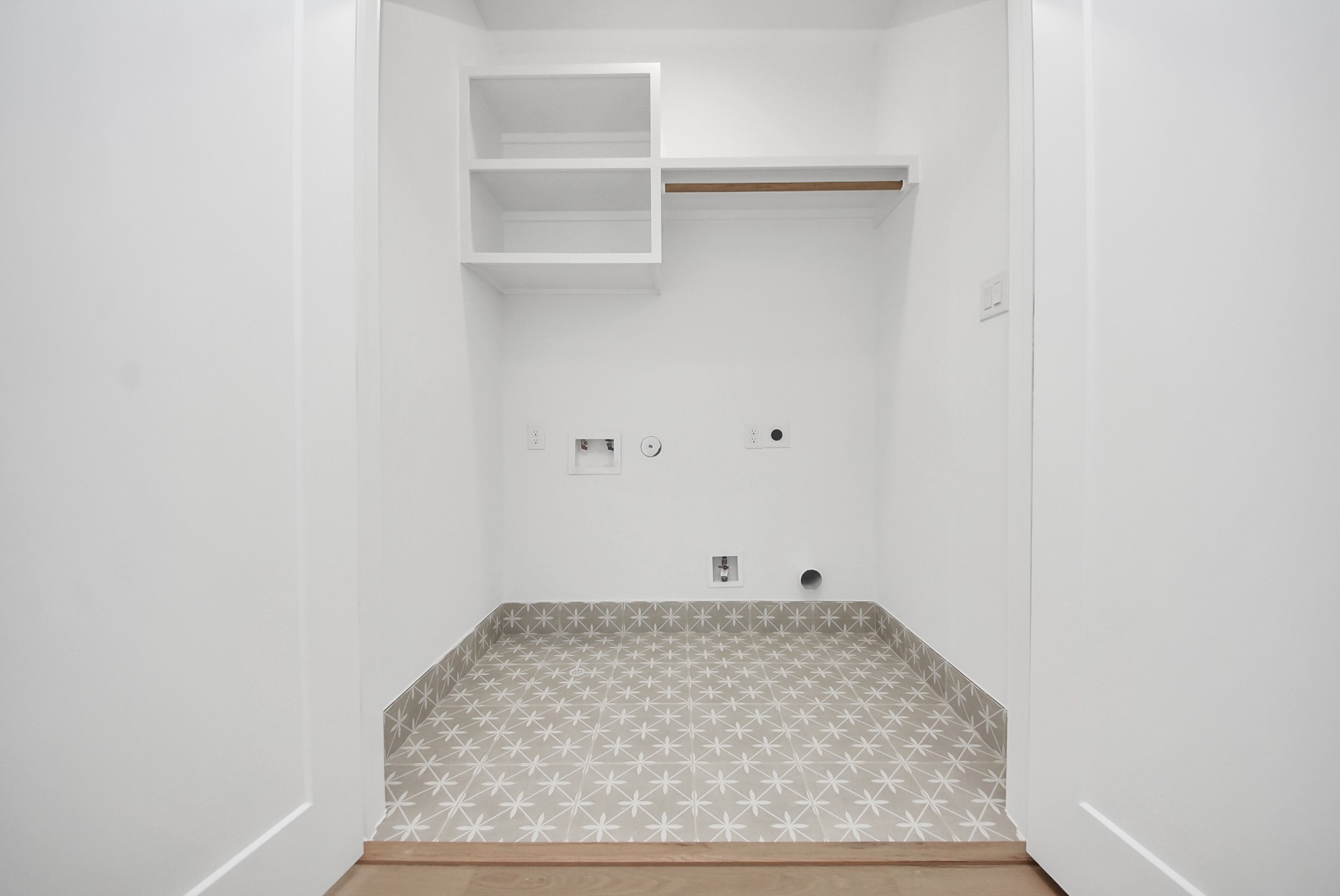 923 Fisher Street, Unit A Houston, TX 77018 - Photo 18 of 47 A compact yet functional laundry nook with washer and dryer hookups, built-in shelving, and a hanging rod for added storage. Patterned tile flooring adds a stylish, modern touch.