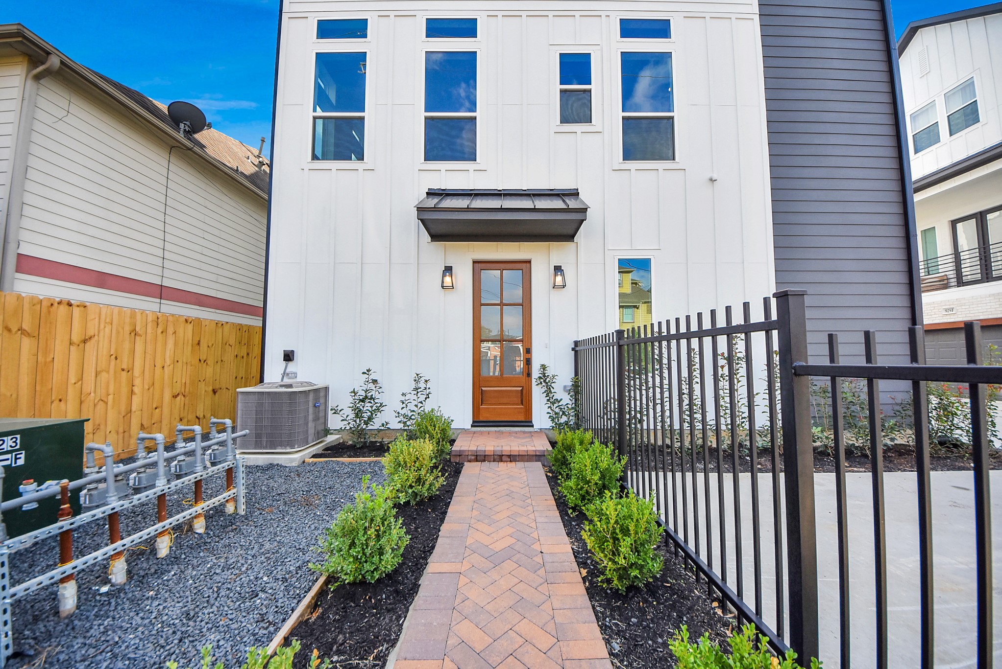 923 Fisher Street, Unit A Houston, TX 77018 - Photo 2 of 47 A thoughtfully designed exterior with expansive windows, a warm wood front door, and a brick walkway framed by manicured landscaping and a black metal fence—setting the tone for refined, effortless living from the moment you arrive.