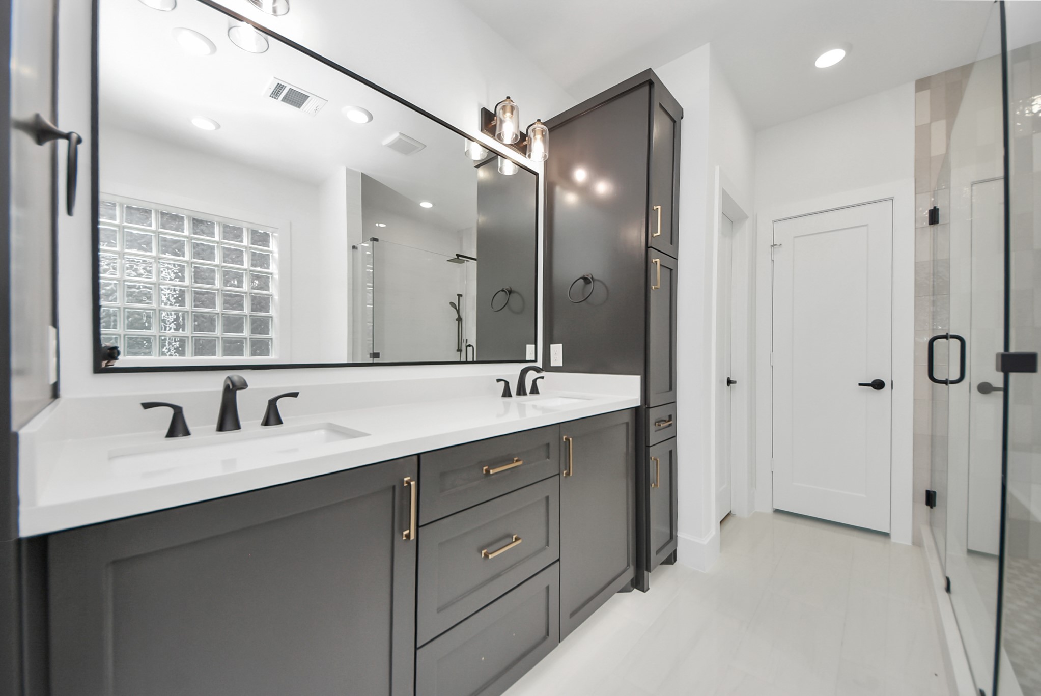 923 Fisher Street, Unit A Houston, TX 77018 - Photo 24 of 47 A modern bathroom featuring dual sinks, black fixtures, and stylish cabinetry. A spacious glass-enclosed shower and ample lighting create a bright, inviting environment.