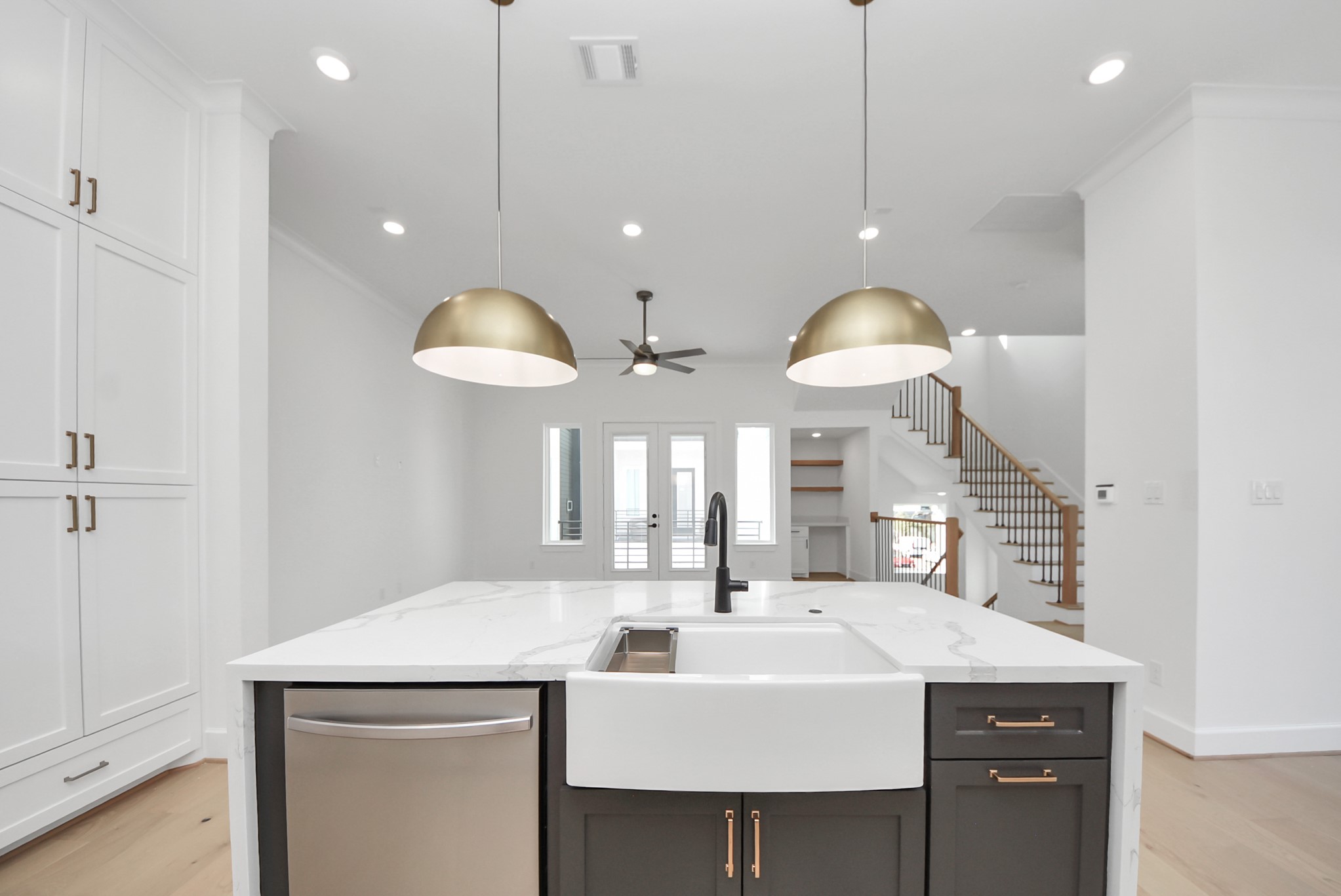 923 Fisher Street, Unit A Houston, TX 77018 - Photo 30 of 47 Welcome to this open-concept kitchen and living area, designed for modern living. The large island with farmhouse sink and elegant pendant lighting anchors the space, while bright natural light fills the room and highlights the seamless flow to the staircase leading upstairs.