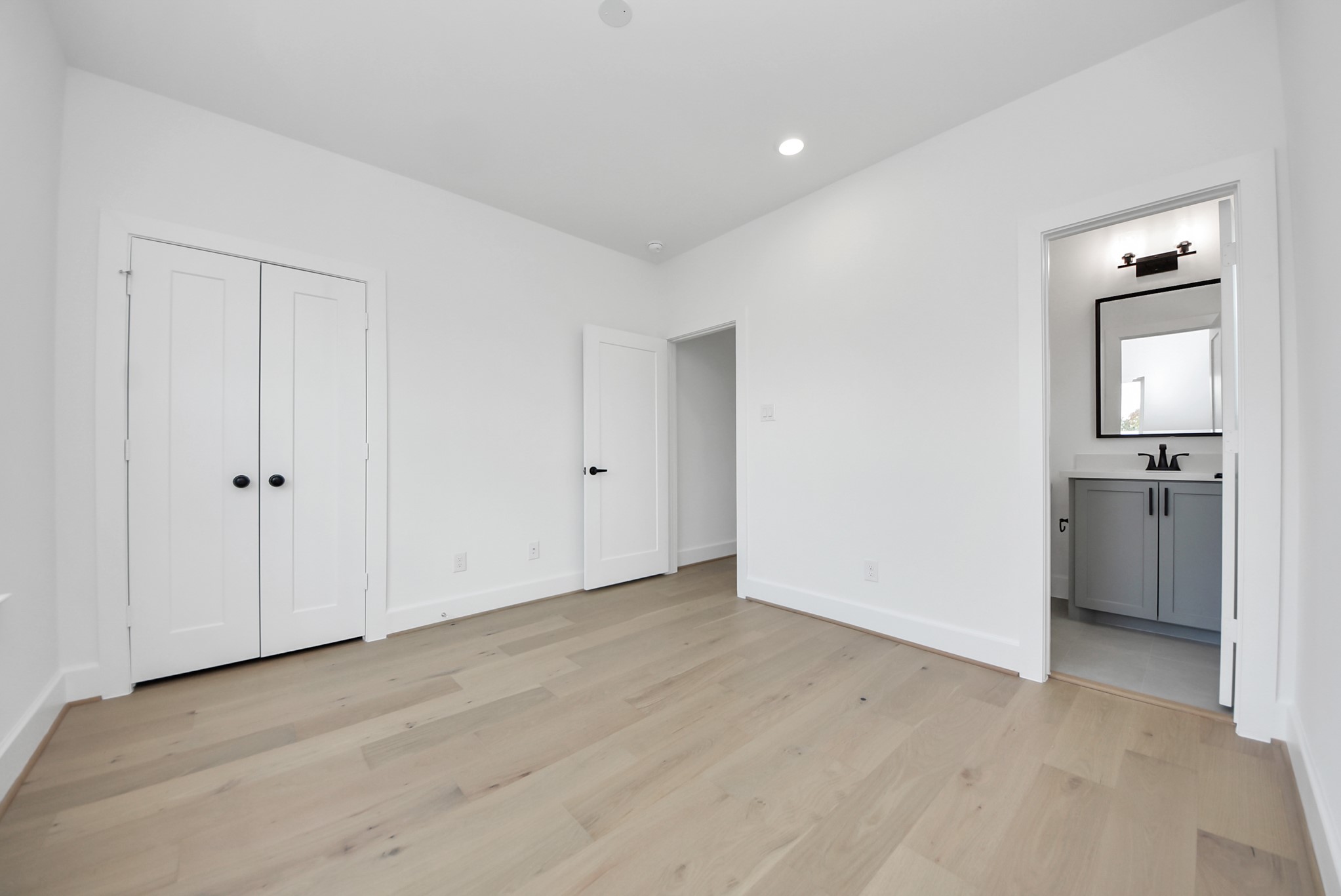 923 Fisher Street, Unit A Houston, TX 77018 - Photo 31 of 47 Step into this bright, modern bedroom, featuring ample natural light and a clean, neutral palette. The double-door closet and en-suite bathroom with a sleek vanity and mirror make it a personal retreat ready for your style.
