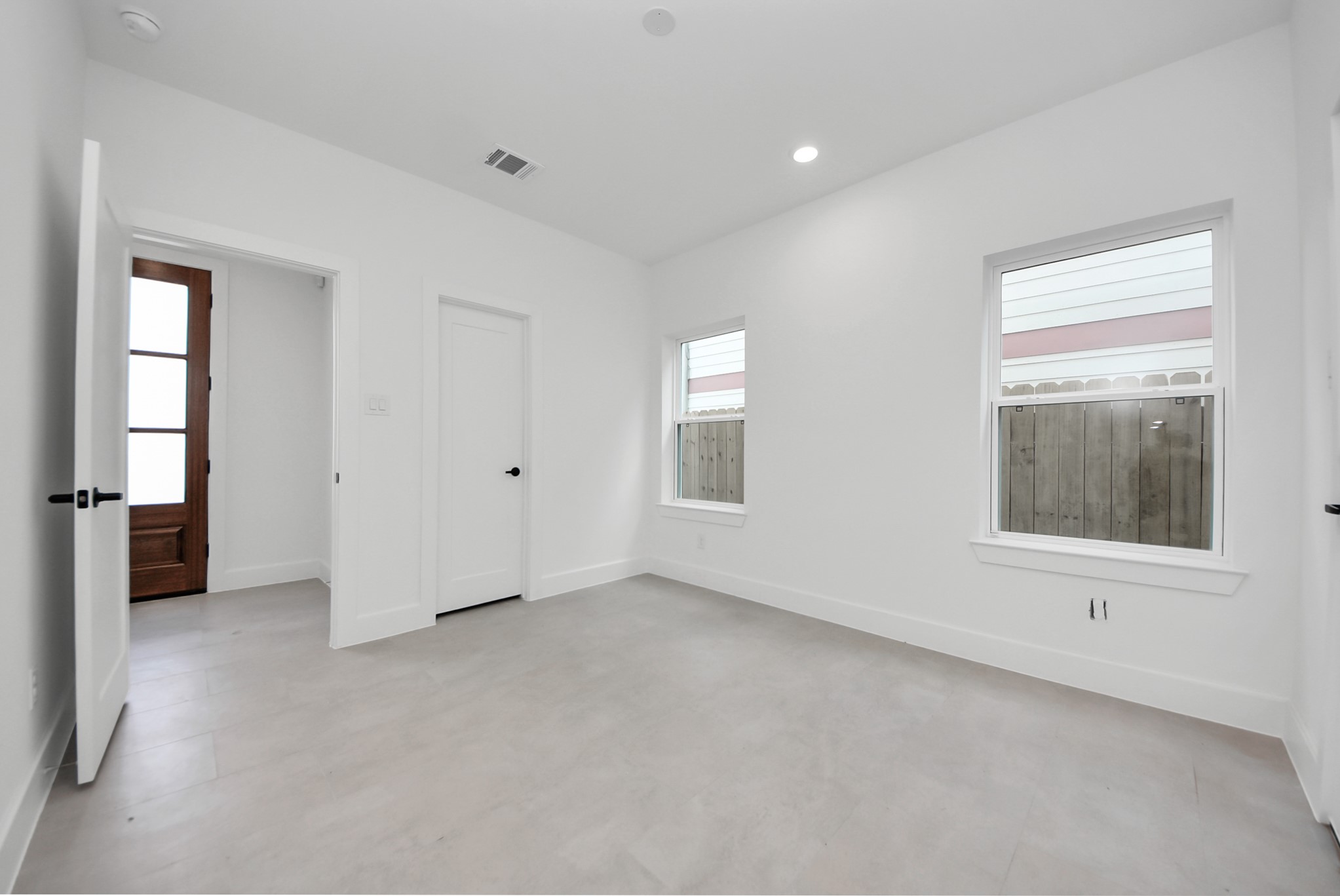 923 Fisher Street, Unit A Houston, TX 77018 - Photo 34 of 47 Enjoy this bright, welcoming room with light wood floors and natural light streaming through two large windows. A functional closet and wooden door provide practical storage, creating a comfortable space for living or working.