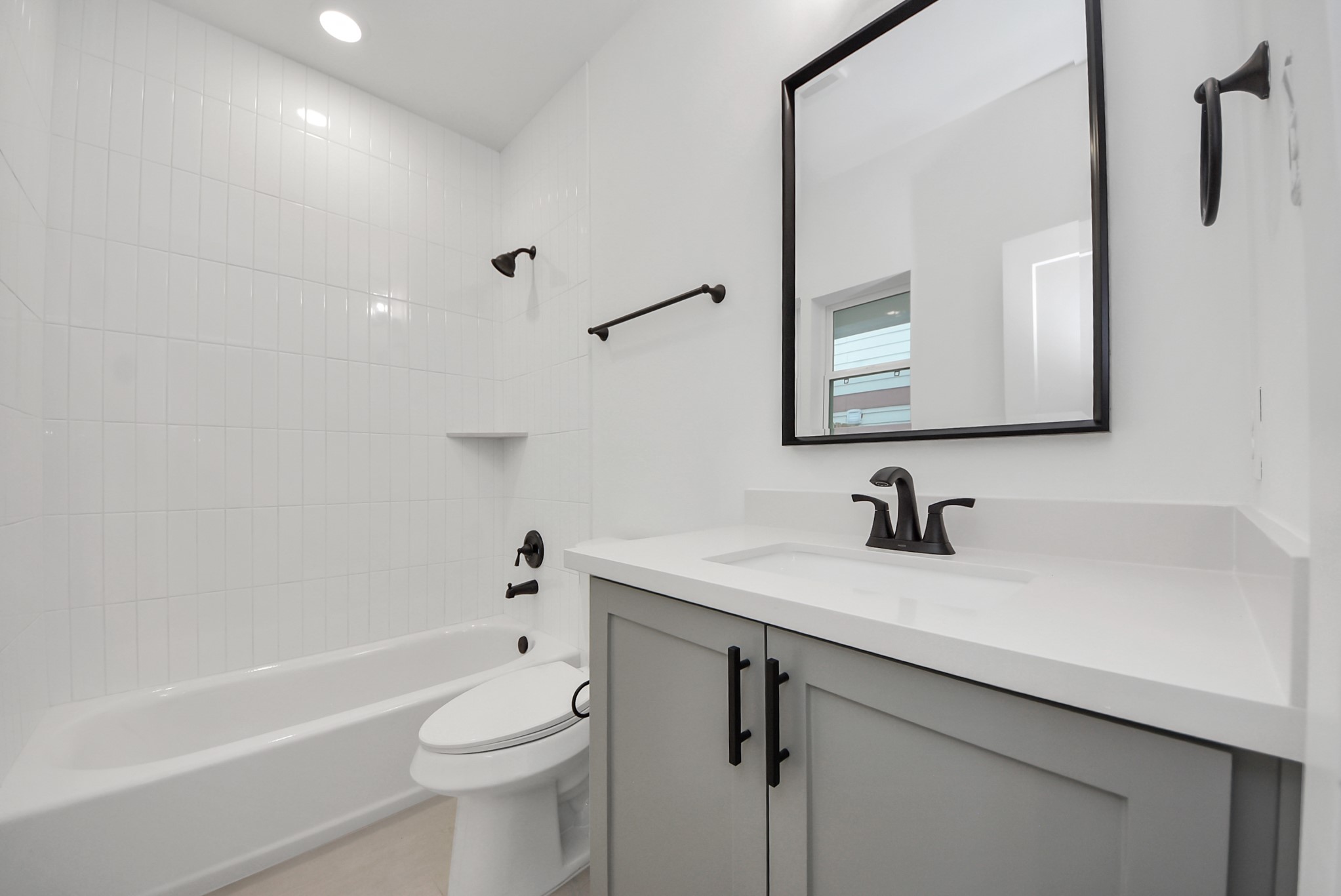 923 Fisher Street, Unit A Houston, TX 77018 - Photo 37 of 47 This bathroom continues the modern aesthetic with a tiled bathtub and shower combination, a black-framed mirror, and crisp, white cabinetry, providing both style and functionality.