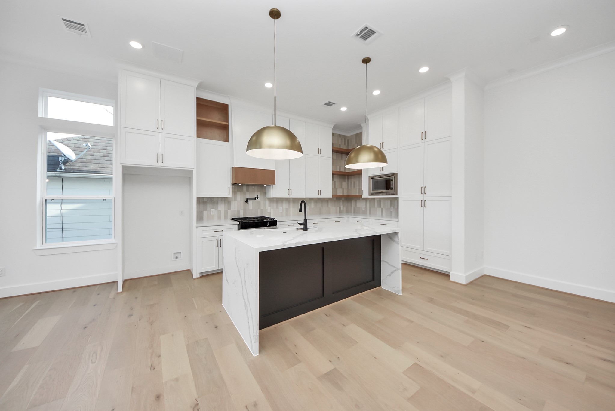 923 Fisher Street, Unit A Houston, TX 77018 - Photo 9 of 47 A sleek, thoughtfully designed kitchen with white cabinetry, marble-style countertops, and a spacious island ideal for both casual dining and entertaining. Hardwood floors and natural light create a bright, welcoming atmosphere tailored for modern living.