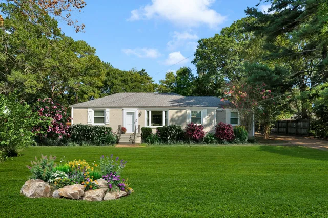 a front view of a house with garden and trees