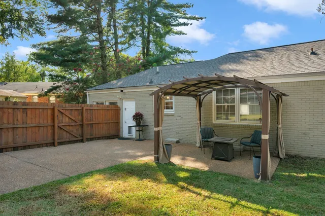 a view of a white house next to a yard with wooden fence