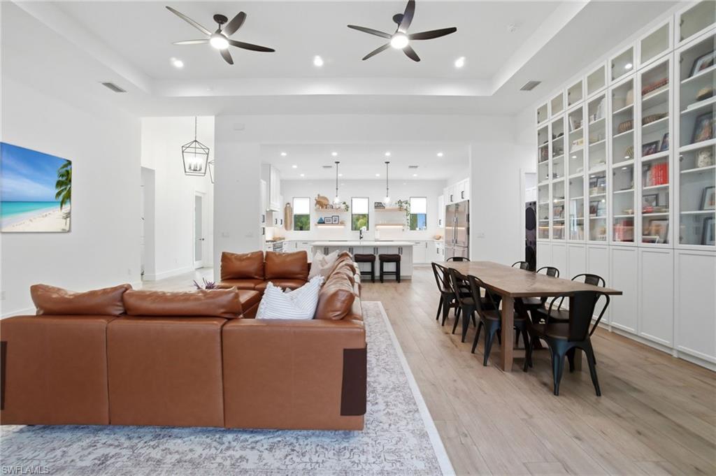522 31st Street Southwest Naples, FL 34117 - Photo 12 of 38 Open-concept living space featuring wood-finish flooring, recessed lighting, ceiling fans, and a full wall of built-in cabinetry with glass-front uppers